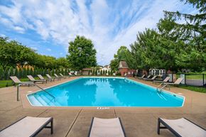 Canal Winchester apartment for rent - A large outdoor swimming pool surrounded by lounge chairs and trees.