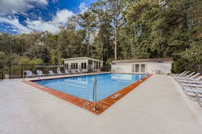 Alpharetta apartment for rent - A large outdoor swimming pool surrounded by trees and lounge chairs.