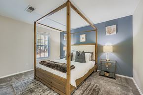 Alpharetta apartment for rent - A bedroom with a four poster bed and a rug on the floor.