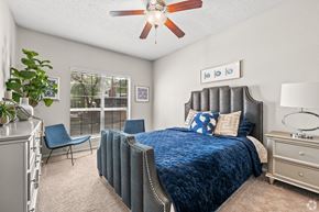 Dallas apartment for rent - A bedroom with a bed, chair, and ceiling fan.
