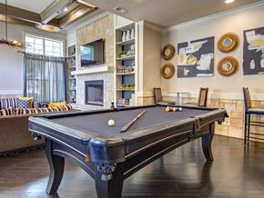 Alpharetta apartment for rent - A pool table is in the middle of a room with a fireplace and a TV.
