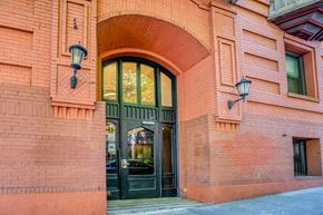 Portland apartment for rent - A red brick building with a black door and two lamps on either side at Clay & Tiffany, Portland, 97201