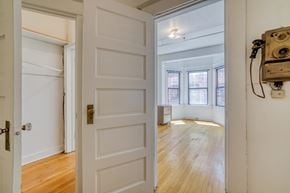 Portland apartment for rent - A white door with a brass handle is open to a room with wooden floors and a window.
