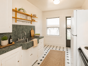 Portland triplex for rent - A kitchen with white cabinets and a green counter top.