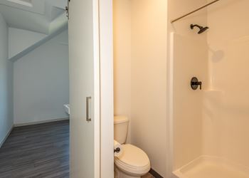 A white toilet in a small bathroom with a white tub.