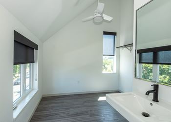A bathroom with a white sink and a ceiling fan.