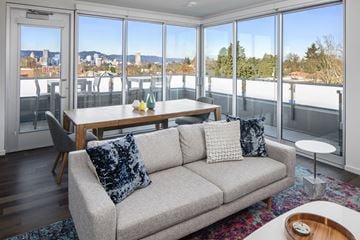 Portland apartment for rent - A living room with a grey couch and a table with a vase of flowers on it.