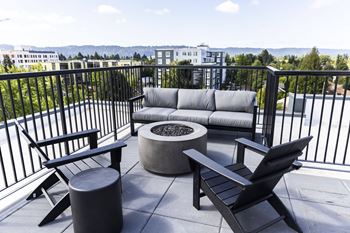 A balcony with a couch and chairs and a fire pit