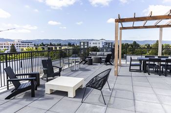 A rooftop patio with tables and chairs and a pergola