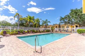 Fort Pierce apartment for rent - A pool surrounded by a white fence and palm trees.