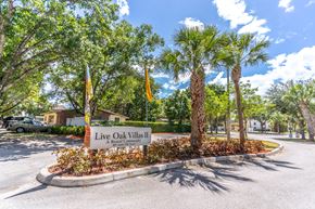 Fort Pierce apartment for rent - A sign for Live Oak Villas II, a rental community, is displayed in front of a landscaped area with palm trees.
