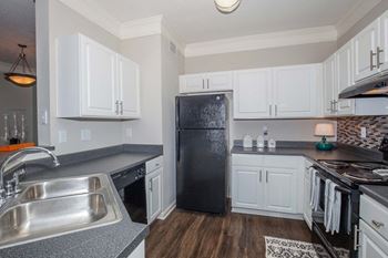 A kitchen with a black refrigerator and white cabinets.