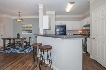 A kitchen with a white island and a black fridge.