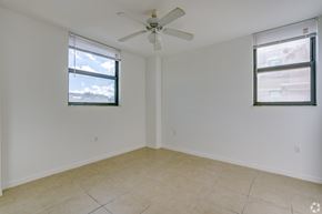 Miami apartment for rent - A room with a ceiling fan and two windows.
