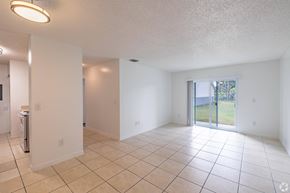 Homestead apartment for rent - A spacious room with tiled flooring and a sliding glass door leading to a backyard.