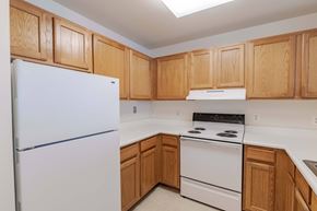 Herndon apartment for rent - A kitchen with wooden cabinets and white appliances.at Kendrick Court Senior Apartments, Herndon, VA