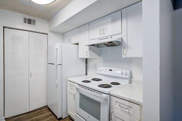 Palm Beach apartment for rent - A white kitchen with a stove, refrigerator, and cabinets.