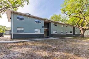 Lakeland apartment for rent - A building with a green and grey exterior is surrounded by trees.