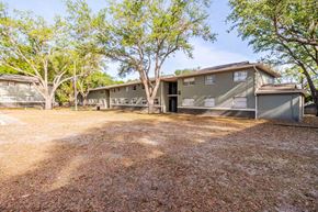 Lakeland apartment for rent - A building with a grey facade surrounded by trees.