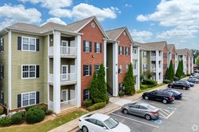 Carrollton apartment for rent - a row of apartment buildings with cars parked in a parking lot at Magnolia Lake Apartments, Carrollton, GA, 30117