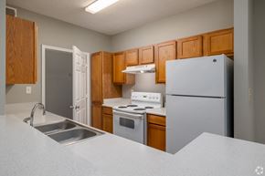 Carrollton apartment for rent - a kitchen with white appliances and wooden cabinets at Magnolia Lake Apartments, Georgia