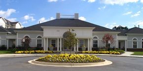 Landover apartment for rent - A large white house with a grey roof and a circular flower bed in front.