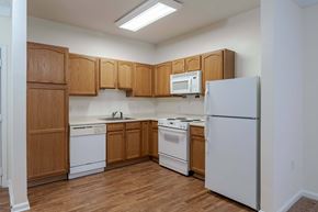Manassas Park apartment for rent - A kitchen with wooden cabinets and white appliances.