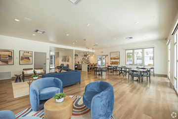 Miami apartment for rent - a living room with blue chairs and tables and a large window