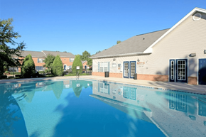 Mooresville apartment for rent - A swimming pool in front of a building with a blue sky in the background.