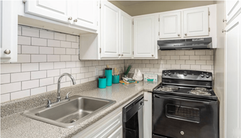A kitchen with white cabinets and black appliances