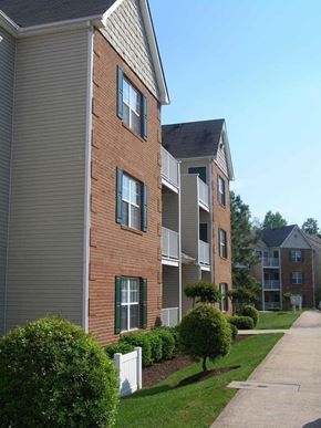 Chester apartment for rent - Apartment building with a white fence and green bushes in front.