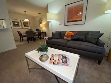 South Riding apartment for rent - A living room with a grey couch, a white coffee table, and a painting on the wall.