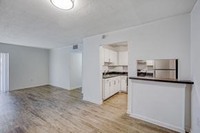 Miami apartment for rent - an empty living room with a kitchen in the background
