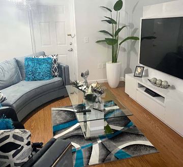 Miami apartment for rent - A living room with a grey couch, a glass coffee table, and a television.