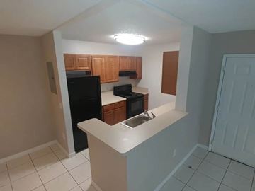 Florida City apartment for rent - A kitchen with black appliances and wooden cabinets.