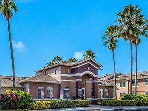 Miami Gardens apartment for rent - A house with a brown roof and a red door is surrounded by palm trees.