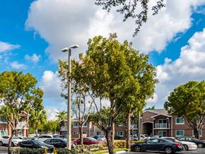Miami Gardens apartment for rent - A parking lot with cars and trees in front of apartment buildings.