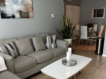 Homestead apartment for rent - A grey couch with striped pillows sits in a living room with a white coffee table in front of it.