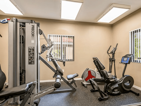 Miami apartment for rent - A gym with a variety of equipment including a treadmill, a stationary bike, a leg press machine, and a cable machine.