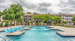 Greenville apartment for rent - a swimming pool with chaise lounge chairs and umbrellas in front of an apartment building at The Bristol Apartments, Greenville, SC
