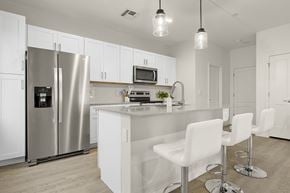 Phoenix townhouse for rent - a kitchen with a large island with white chairs and a stainless steel refrigerator