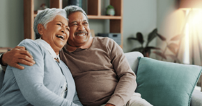 Hugo apartment for rent - An older couple is sitting on a couch, smiling and laughing together.