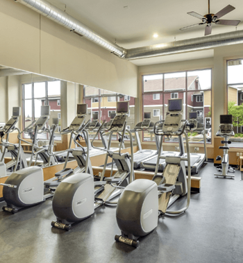 A gym with cardio equipment and windows in a building