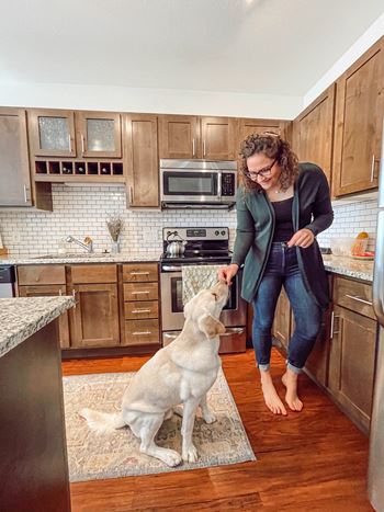 A woman petting a dog in a kitchen
