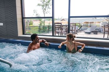 A man and a woman sitting in the water in a hot tub