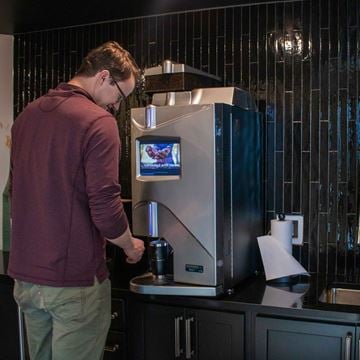 Hugo apartment for rent - A man is using a coffee machine in a kitchen.