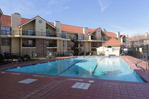Dallas apartment for rent - A large outdoor swimming pool surrounded by a red tile floor and apartment buildings.