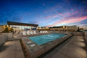 Salt Lake City apartment for rent - A swimming pool with lounge chairs and a building in the background.