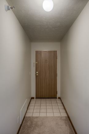 Gretna apartment for rent - A hallway with a brown door and tiled floor.