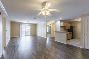 Omaha apartment for rent - A spacious living room with a ceiling fan and sliding glass doors.